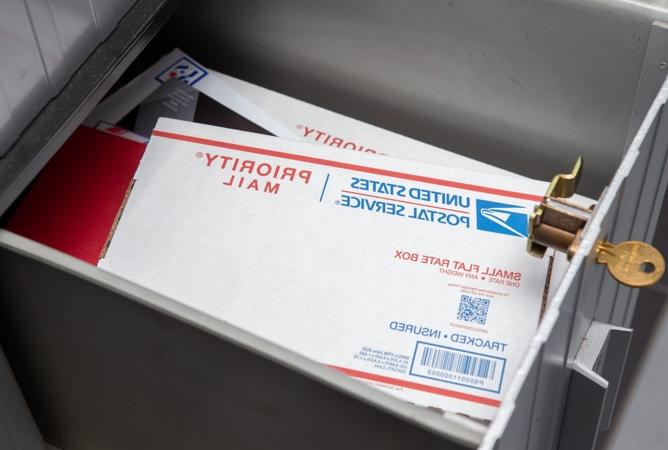 一个邮政信箱，钥匙插在锁里，邮件放在盒子里.